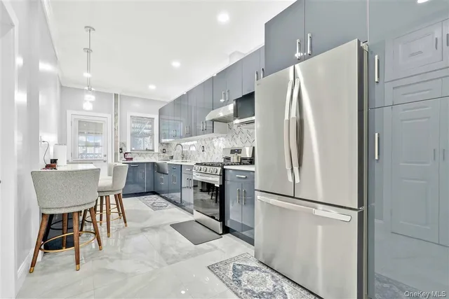 a kitchen with stainless steel appliances granite countertop a sink a stove a refrigerator cabinets and chairs