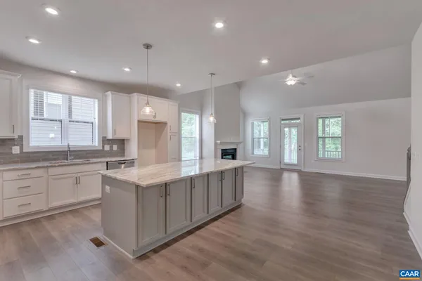 a large kitchen with stainless steel appliances granite countertop a large center island attached withe living room