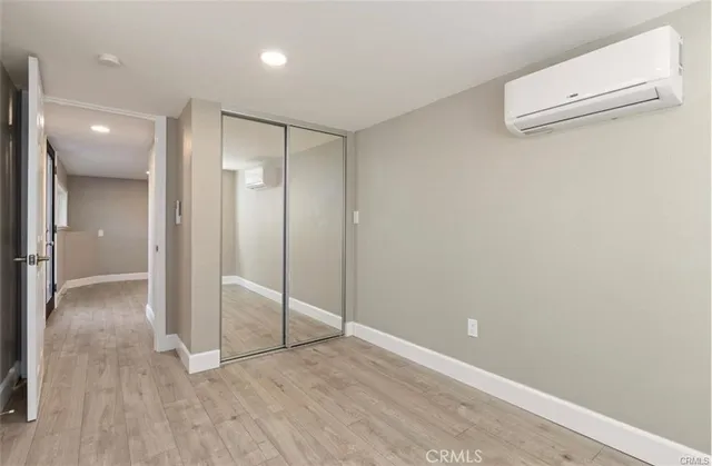 an empty room with wooden floor and mirror
