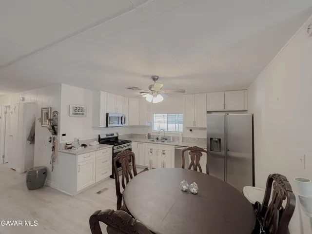 a kitchen with stainless steel appliances granite countertop a refrigerator a stove a sink dishwasher a dining table and chairs with wooden floor