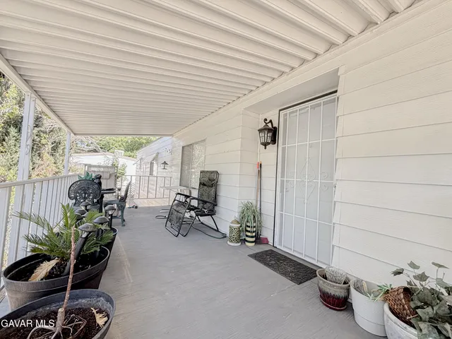 a view of a patio with table and chairs potted plants and floor to ceiling window