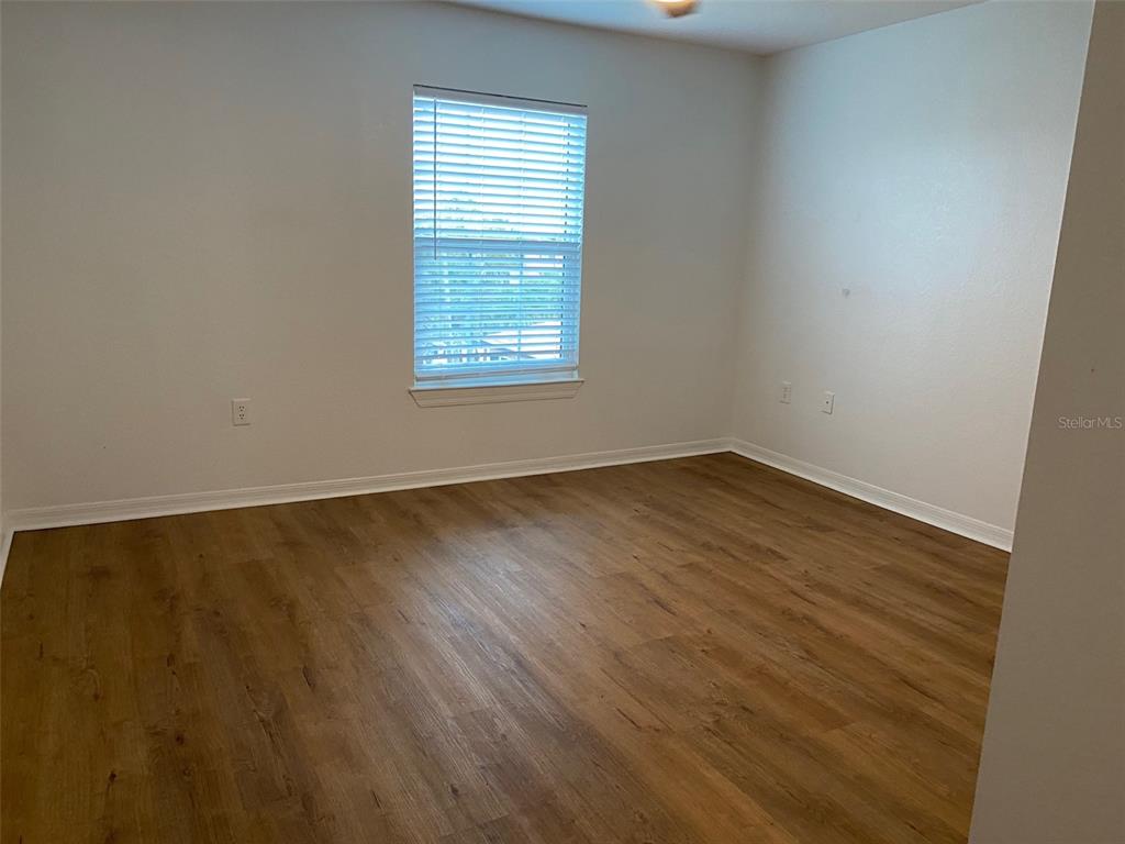 5447 Vineland Road, Unit 1303 Orlando, FL 32811 - Photo 11 of 18 an empty room with wooden floor and windows