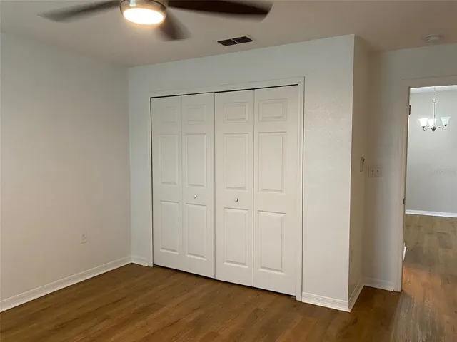 a view of an empty room with wooden floor and closet