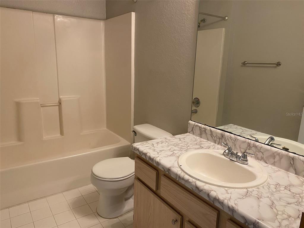 5447 Vineland Road, Unit 1303 Orlando, FL 32811 - Photo 13 of 18 a bathroom with a granite countertop sink toilet and shower