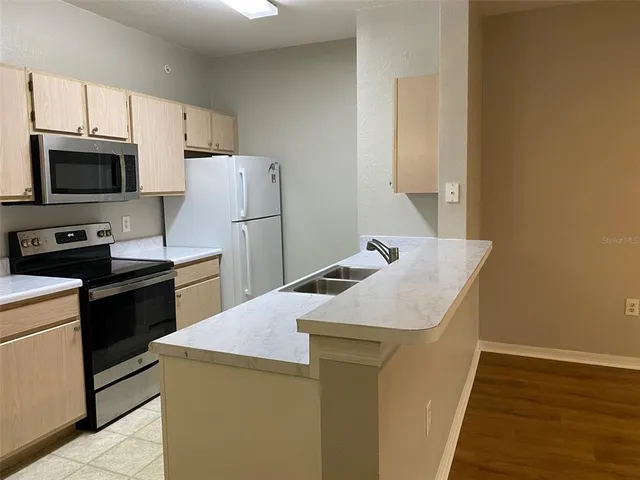 a kitchen with a sink a stove top oven and refrigerator