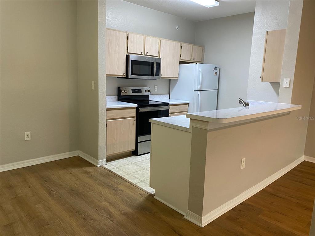 5447 Vineland Road, Unit 1303 Orlando, FL 32811 - Photo 6 of 18 a kitchen with a refrigerator sink and white cabinets