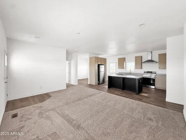a view of an empty room with wooden floor and windows