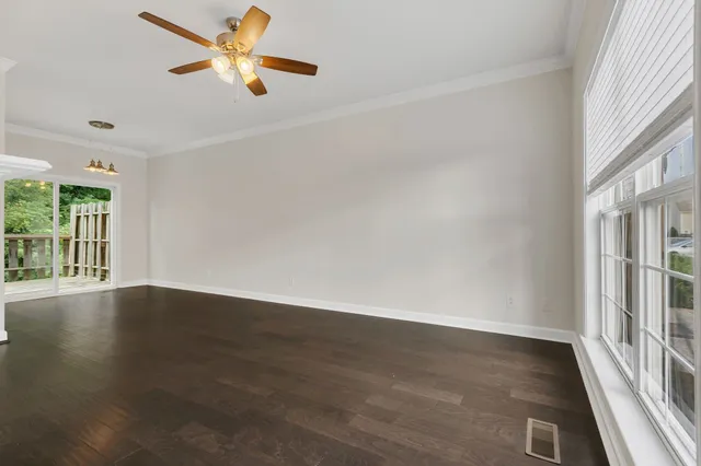 an empty room with wooden floor fan and windows