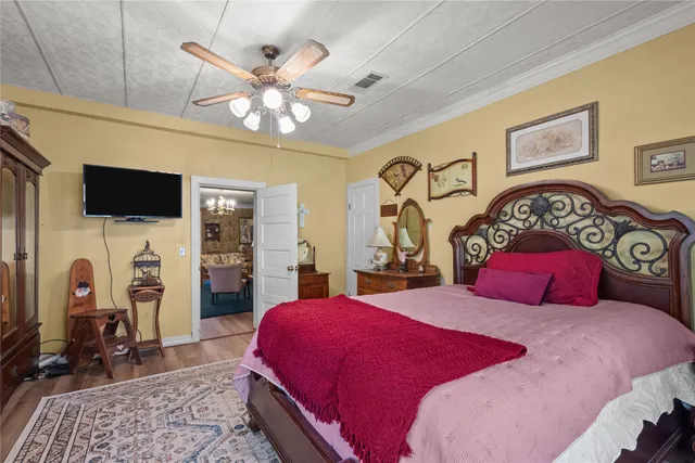 a bedroom with a bed a chandelier and a flat screen tv