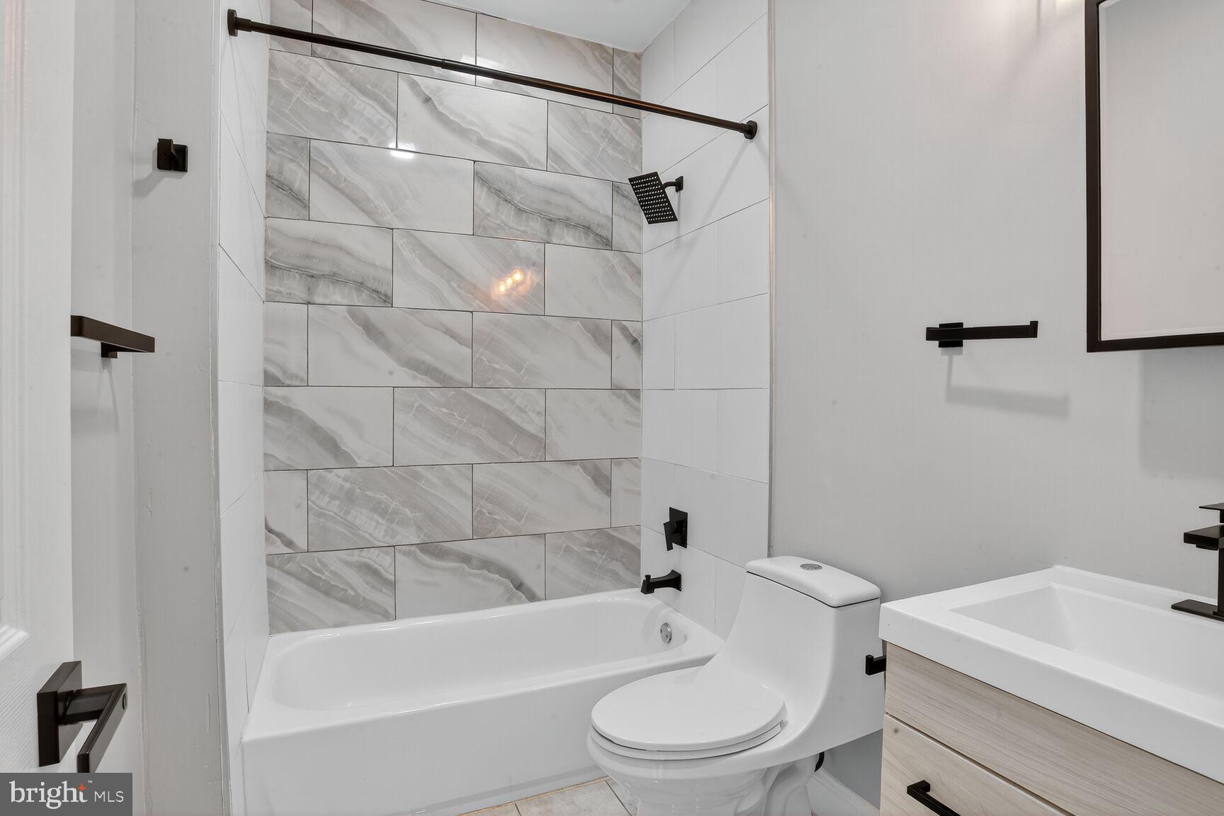 1108 South Carey Street Baltimore, MD 21223 - Photo 14 of 24 a white toilet and tub sitting next to a bathroom sink