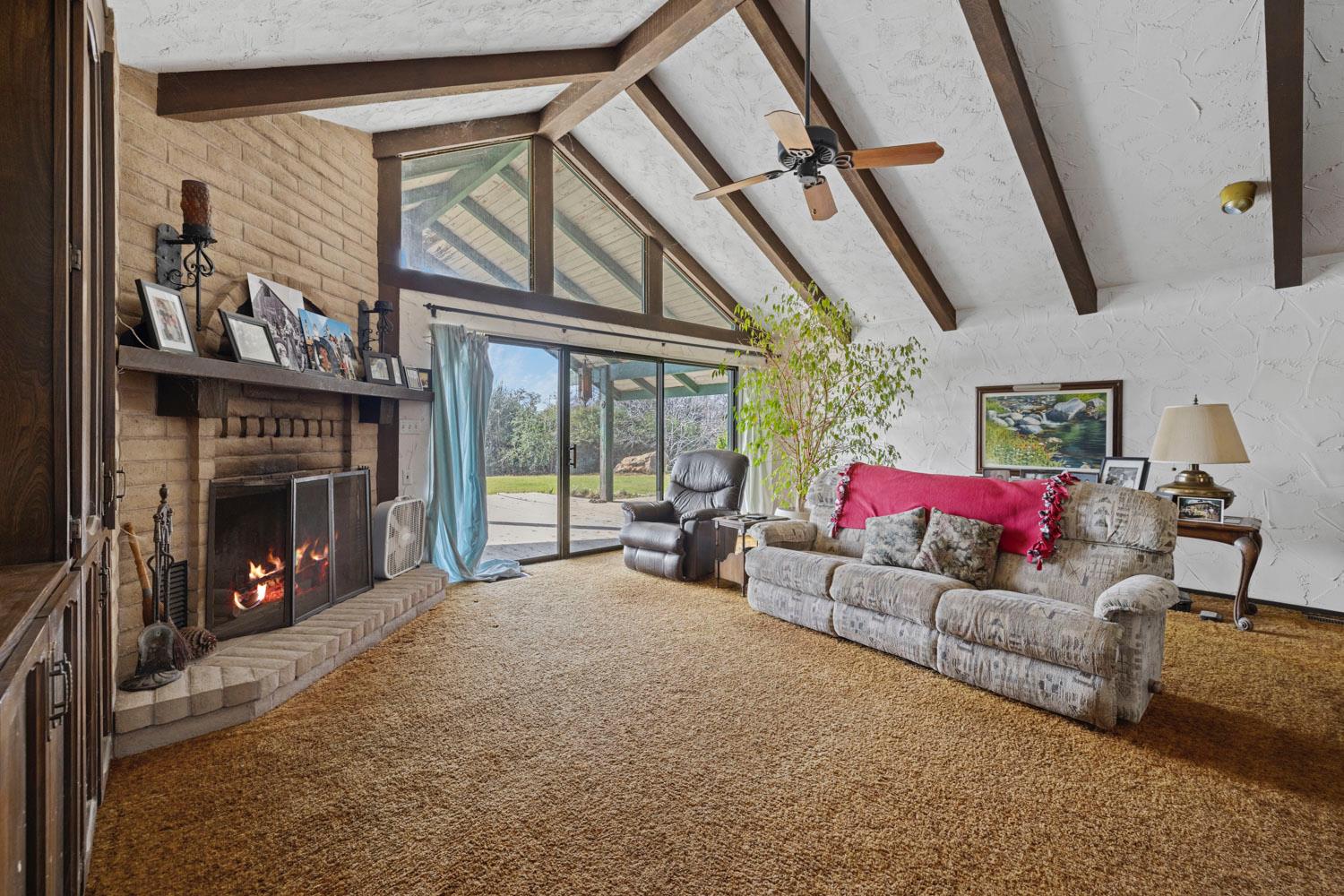 3270 Jackson Valley Road Ione, CA 95640 - Photo 12 of 34 a living room with furniture a fireplace and a floor to ceiling window
