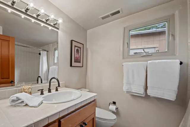 a bathroom with a sink vanity mirror and toilet