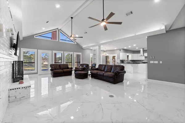 a living room with furniture kitchen view and a chandelier