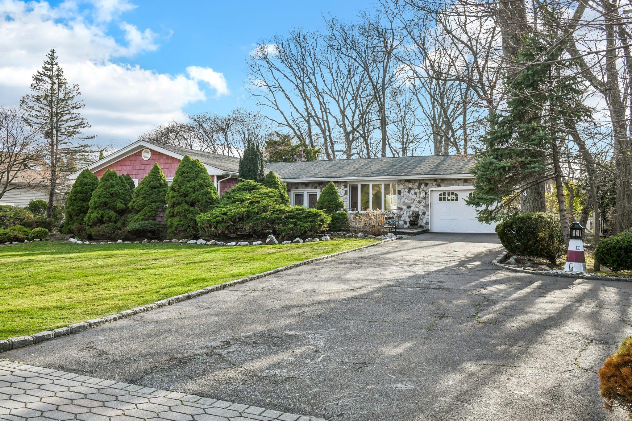 View of front of property featuring driveway, a garage, and a front lawn