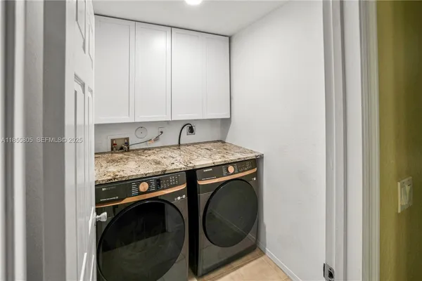 a utility room with granite countertop a sink and a washer dryer