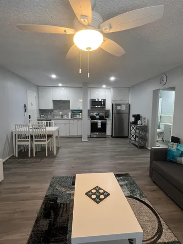 a living room with stainless steel appliances furniture and a kitchen view