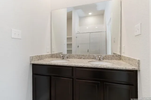 a bathroom with a granite countertop sink and a mirror