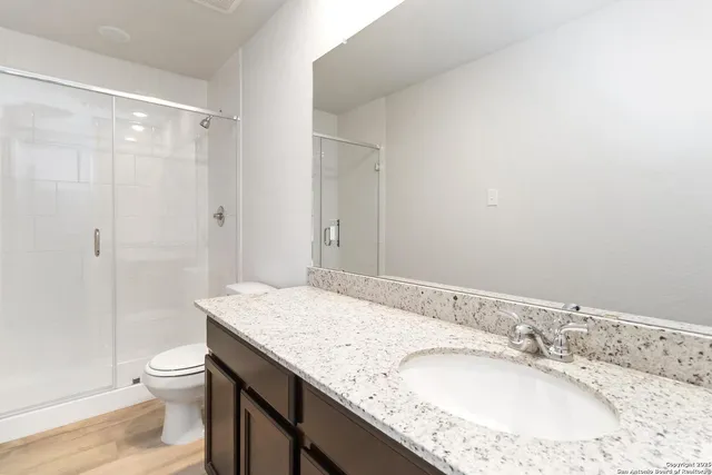 a bathroom with a granite countertop sink a toilet and a large mirror