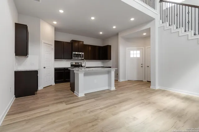 a view of kitchen with stainless steel appliances kitchen island empty cabinets and wooden floor