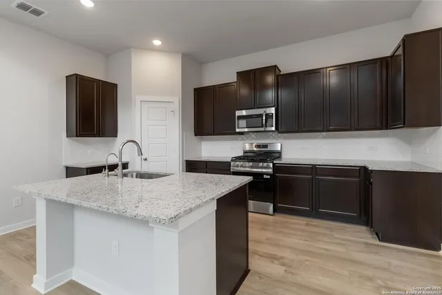 a kitchen with a sink and a stove top oven with wooden floor