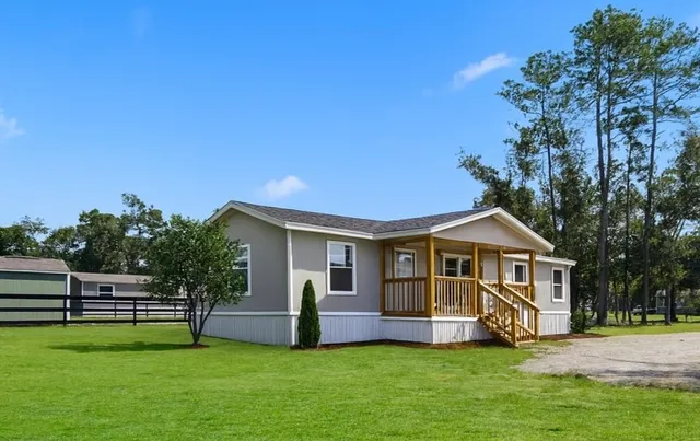 a front view of a house with a yard porch and wooden fence