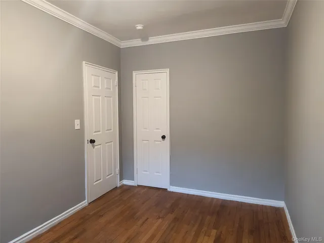 a view of an empty room with wooden floor and closet