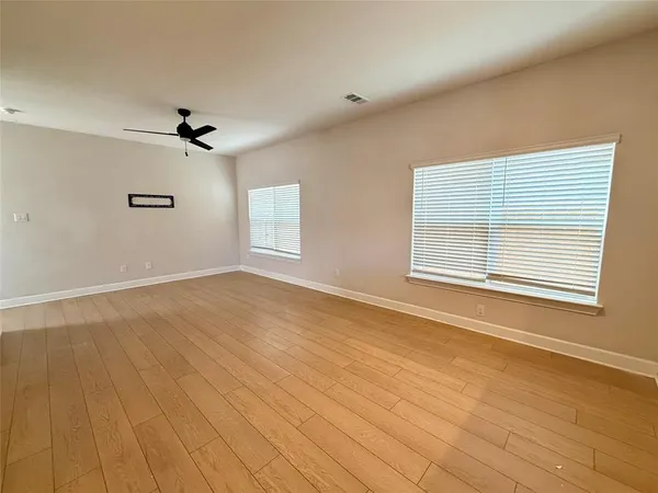 a view of an empty room with a window and wooden floor