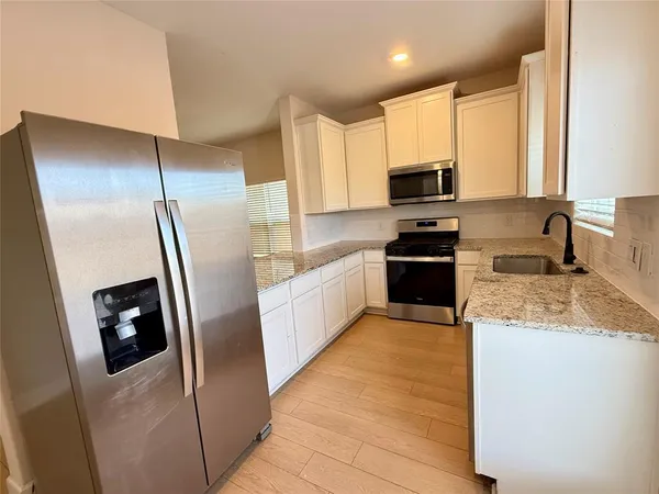 a kitchen with granite countertop a refrigerator a sink a stove a microwave and island