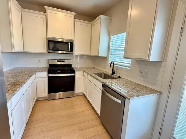 a kitchen with stainless steel appliances granite countertop a sink stove and microwave