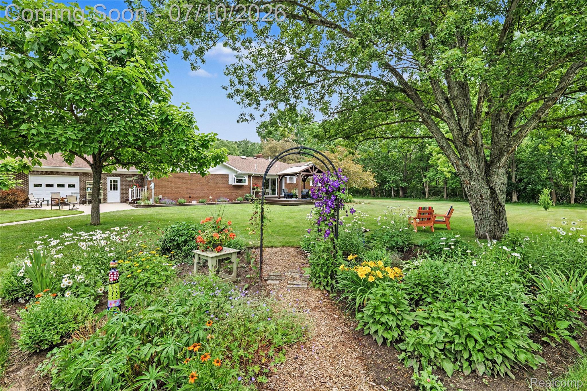 2180 Hurst Road St. Clair, MI 48079 - Photo 32 of 39 Lush garden pathway with an arched trellis and diverse plantings leading to a spacious lawn