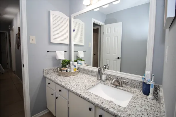 a bathroom with a granite countertop sink a mirror and a shower