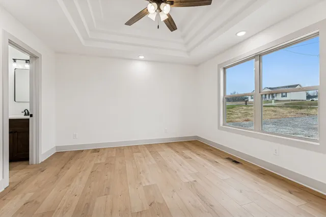 a view of an empty room with a window and wooden floor