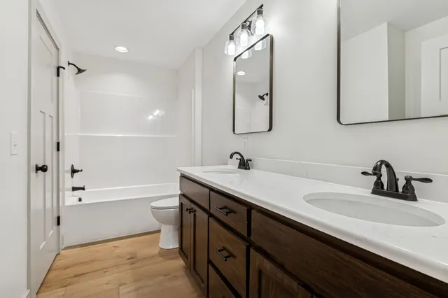 a bathroom with a double vanity sink toilet mirror and bathtub