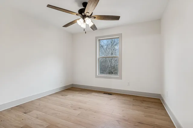 an empty room with a window and a fan