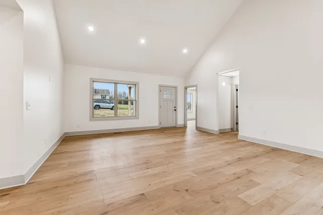 a view of an empty room with a window and wooden floor