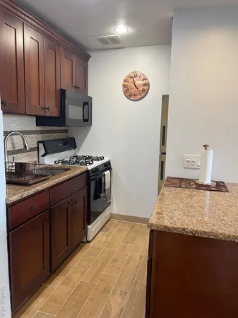 a kitchen with stainless steel appliances granite countertop a stove a sink and a microwave