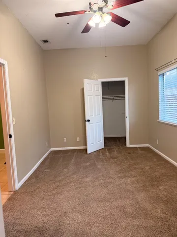 an empty room with chandelier fan and windows