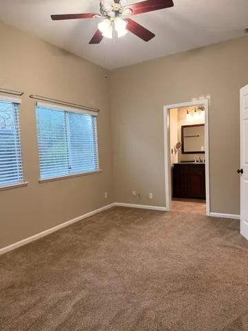 an empty room with chandelier fan and windows