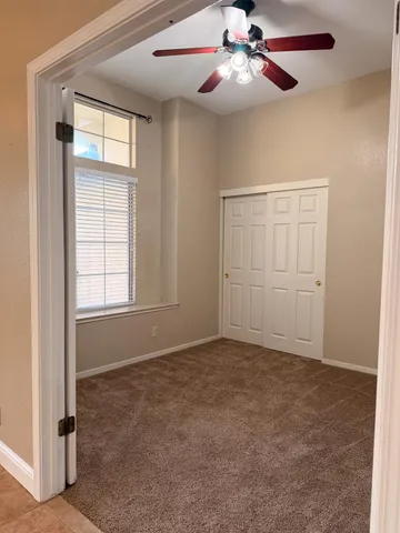 an empty room with windows and fan