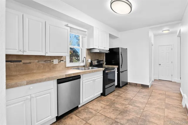 a kitchen with a refrigerator sink and cabinets