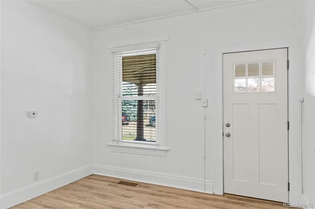 an empty room with wooden floor cabinet and windows