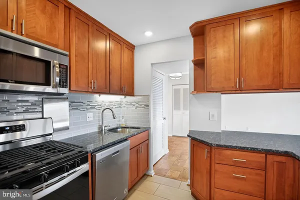 a kitchen with granite countertop wooden cabinets and stainless steel appliances