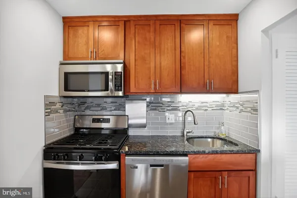 a kitchen with granite countertop stainless steel appliances a stove a sink microwave and cabinets