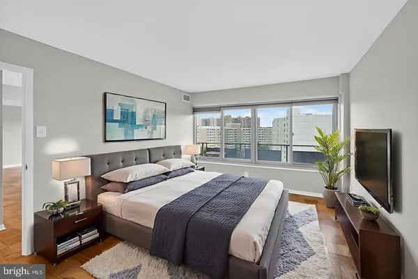 a bedroom with a bed television on desk and a window