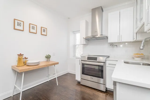 a kitchen with white cabinets stainless steel appliances and wooden floor