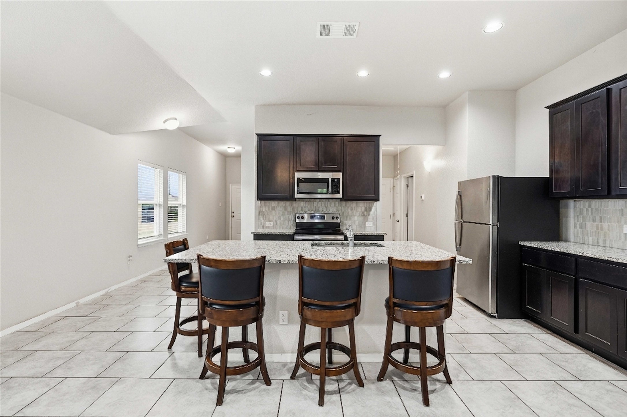 107 Saranac Drive Elgin, TX 78621 - Photo 4 of 17 a kitchen with stainless steel appliances a dining table chairs microwave and refrigerator
