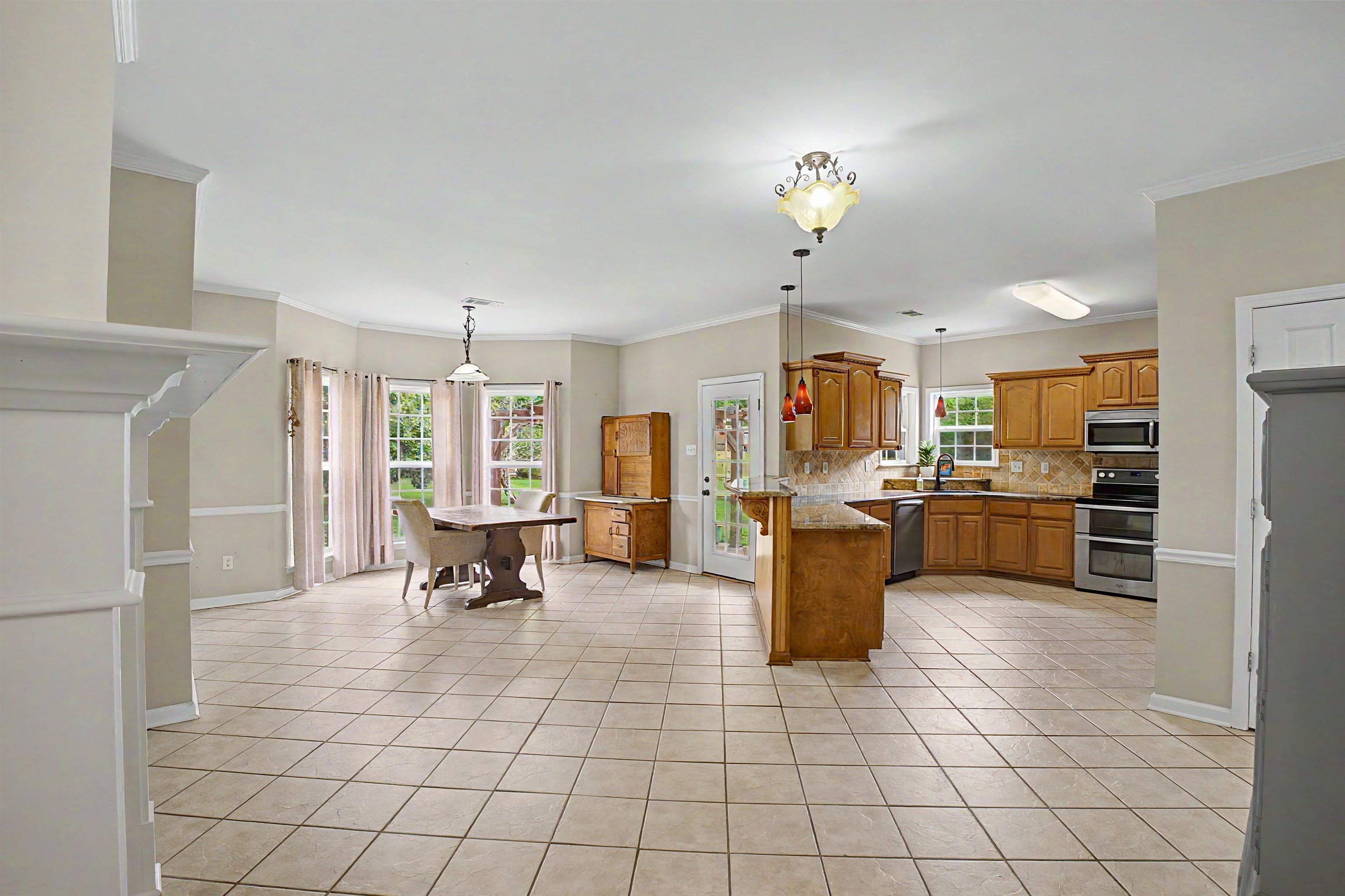 134 Rembert Drive Atoka, TN 38004 - Photo 12 of 38 Expansive kitchen and dining area featuring ceramic tile flooring, wood cabinetry, stainless steel appliances, and a built-in kitchen island