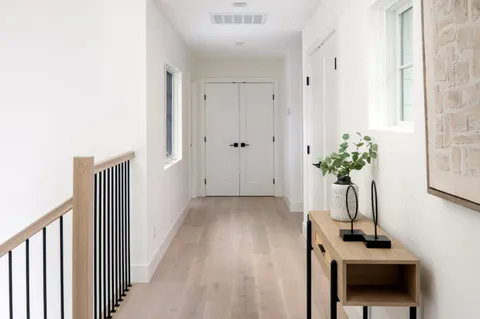 a view of a hallway with wooden floor and a potted plant