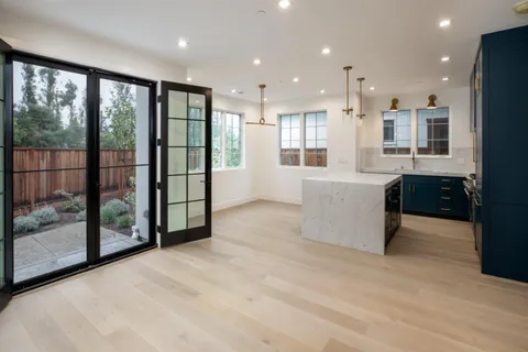 a view of an empty room with a kitchen view and large windows