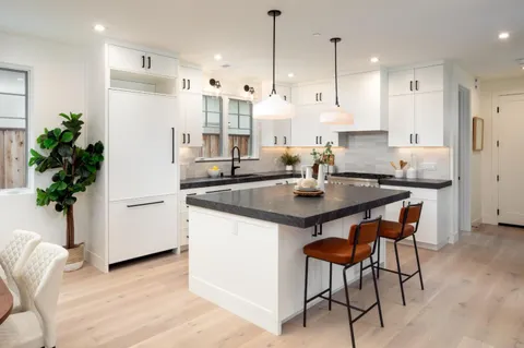 a kitchen with stainless steel appliances a dining table chairs and white cabinets